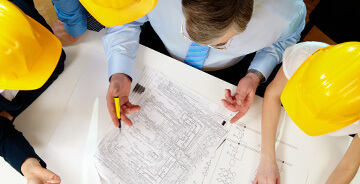 Several men in construction hats reviewing blueprints